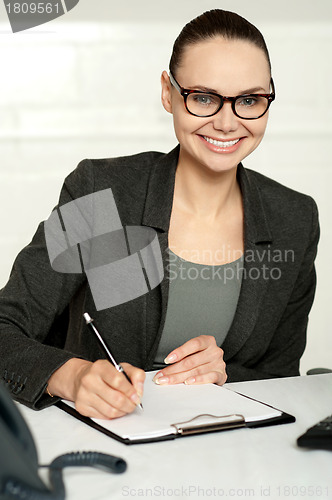 Image of Secretary writing key business notes on clipboard