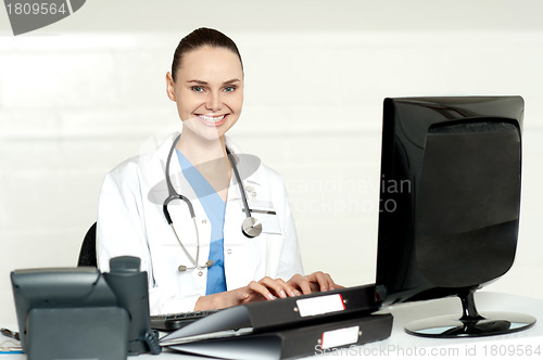 Image of Smiling female doctor working on computer