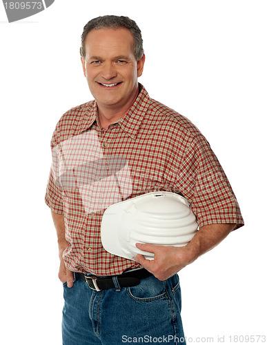 Image of Smiling senior architect holding white safety hat