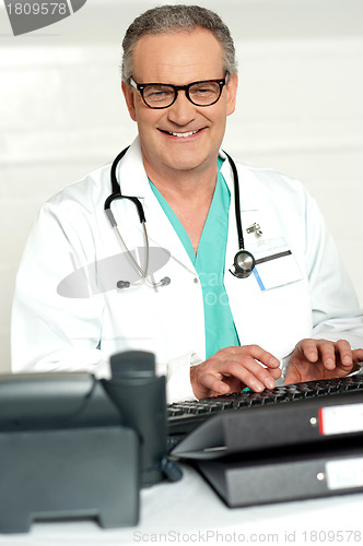 Image of Smiling physician in eye wear typing on keyboard