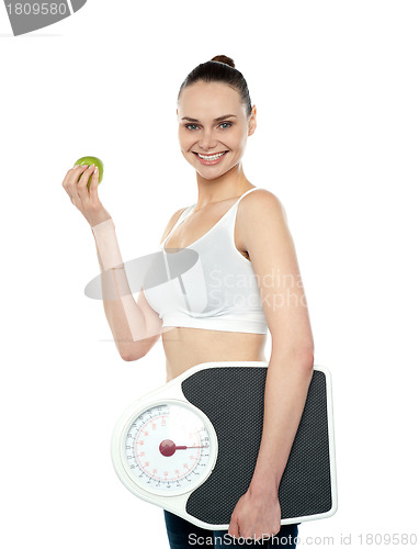 Image of Attractive woman with apple and weight scale