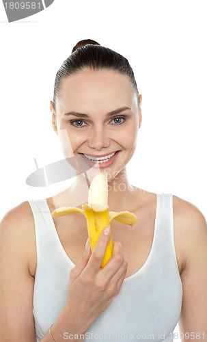 Image of Cheerful fit woman eating banana