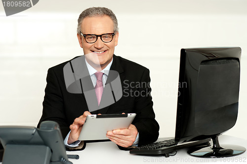 Image of Aged businessman in glasses using tablet
