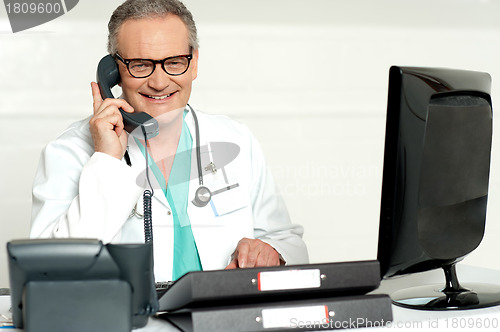 Image of Aged doctor attending call in front of lcd screen