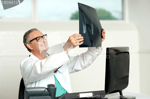 Image of Senior surgeon in glasses looking at x-ray