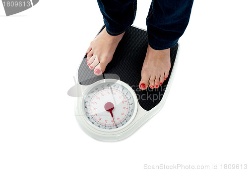 Image of Woman standing on weighing scale, closeup of legs