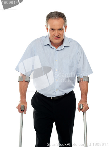 Image of Angry aged man with crutches looking at you