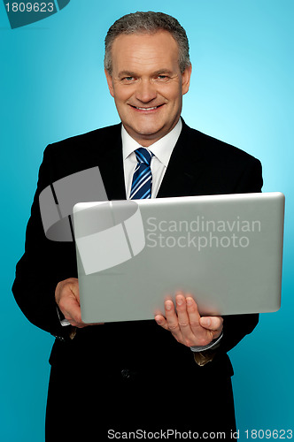 Image of Smiling aged executive holding laptop