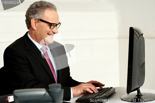 Image of Cheerful aged man working on computer