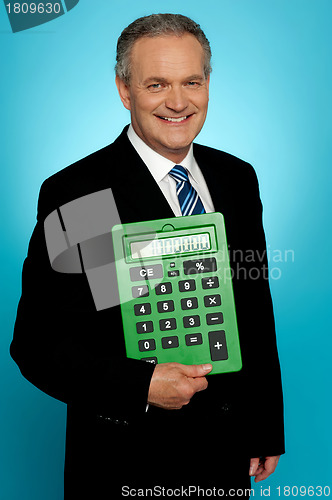 Image of Senior executive posing with big green calculator