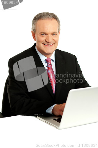 Image of Confident businessman working on laptop