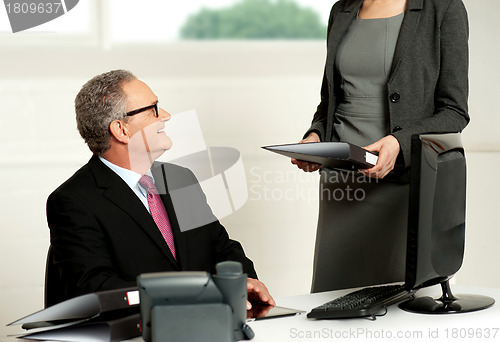 Image of Smiling aged male boss looking at secretary