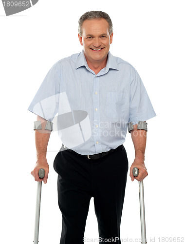 Image of Senior man standing with support of crutches