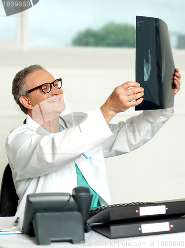 Image of Aged surgeon holding patients x-ray report