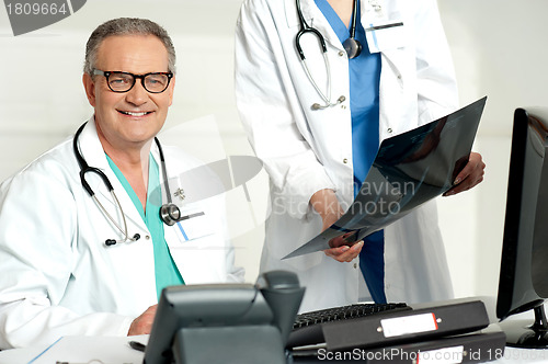 Image of Woman assistant presenting x-ray report to male doctor