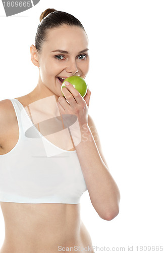 Image of Pretty fit trendy woman eating fresh green apple