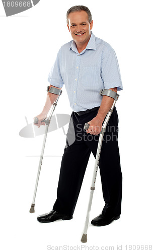 Image of Senior man standing with the help of crutches