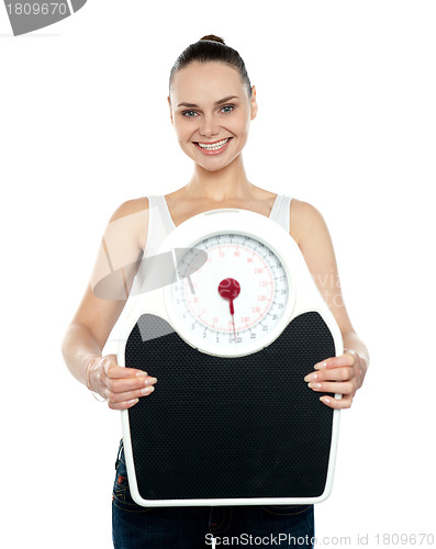 Image of Cheerful young woman holding a weighing