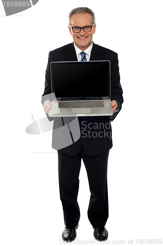 Image of Aged businessman showing newly launched laptop