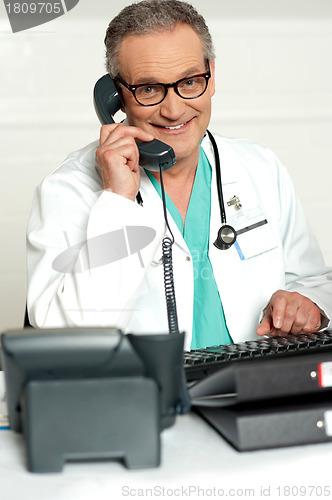 Image of Happy aged medical expert taking on phone
