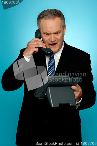 Image of Angry aged corporate man yelling on phone