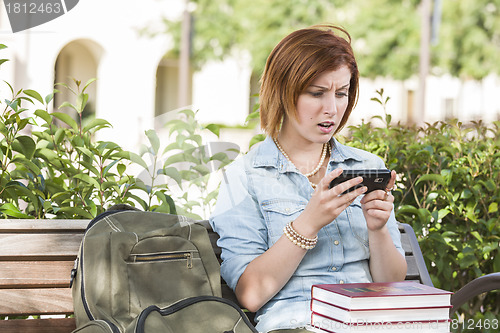 Image of Stunned Young Female Student Outside Texting on Cell Phone