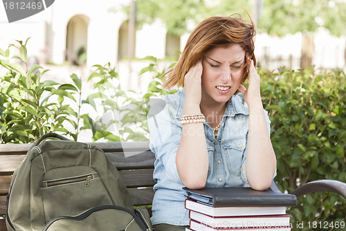 Image of Female Student Outside with Headache Sitting with Books and Back