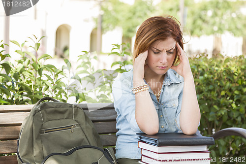 Image of Female Student Outside with Headache Sitting with Books and Back