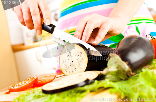 Image of Woman's hands cutting aubergine eggplant