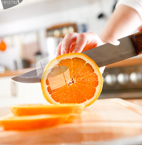 Image of Woman's hands cutting orange