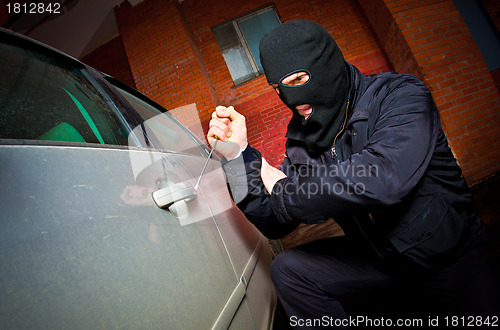 Image of robber and the thief in a mask hijacks the car