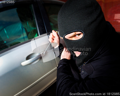 Image of robber and the thief in a mask hijacks the car