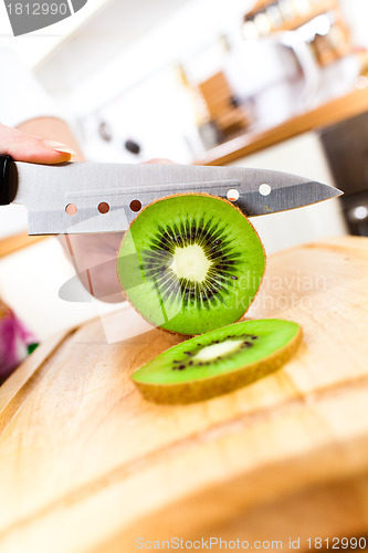 Image of Woman's hands cutting kiwi