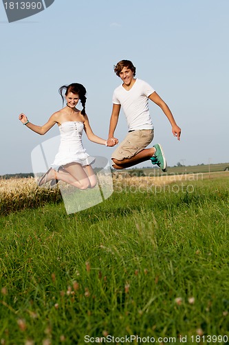 Image of young happy couple jumping outside in summer 