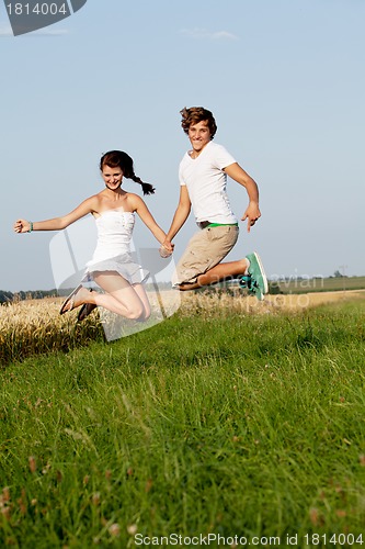 Image of young happy couple jumping outside in summer 