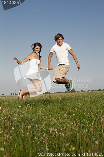 Image of young happy couple jumping outside in summer 