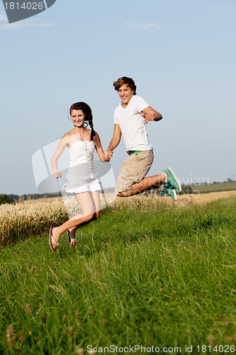 Image of young happy couple jumping outside in summer 