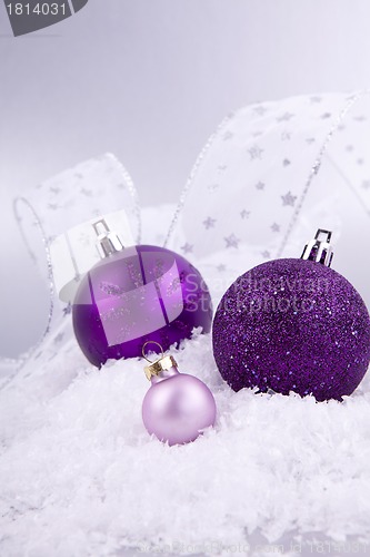 Image of beautiful christmas decoration in purple and silver on white snow