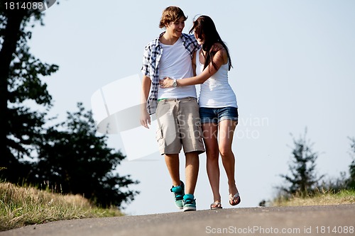 Image of young woman and man is walking on a road in summer outdoor