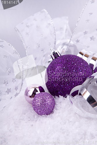 Image of beautiful christmas decoration in purple and silver on white snow