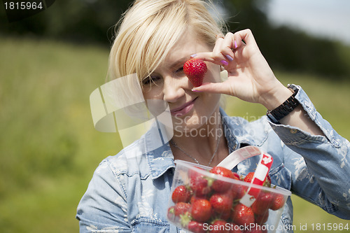 Image of Woman holding up large ripe strawberry