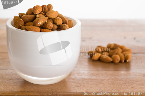 Image of Bowl of raw almond nuts on wooden table