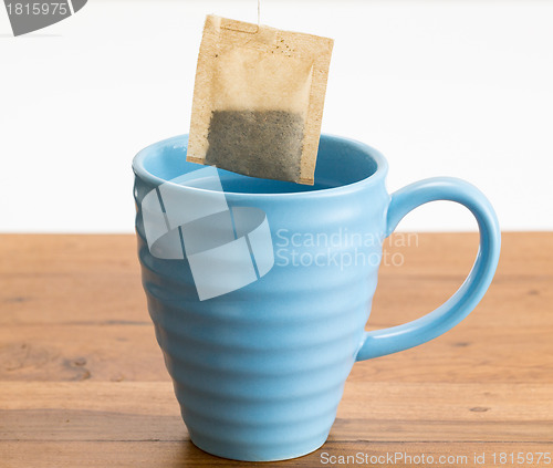 Image of Brown organic green tea bag lowered in mug