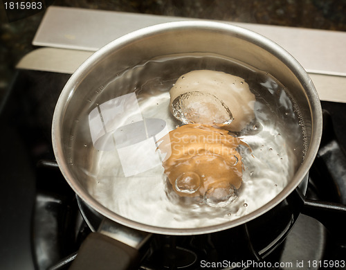 Image of Two boiling eggs in stainless saucepan