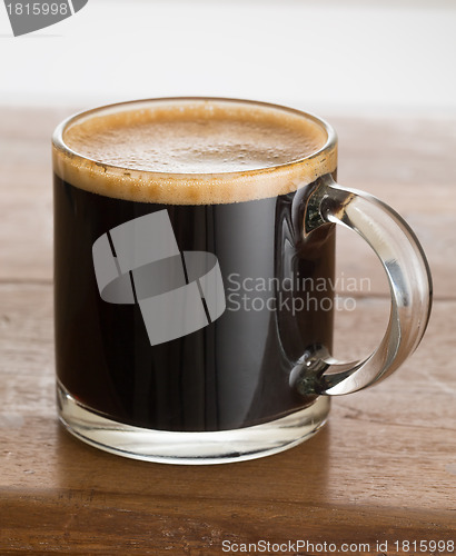 Image of Black coffee and froth in glass mug wood table