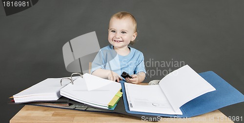 Image of baby with paperwork at wooden desk