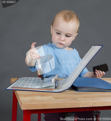 Image of baby with paperwork at wooden desk