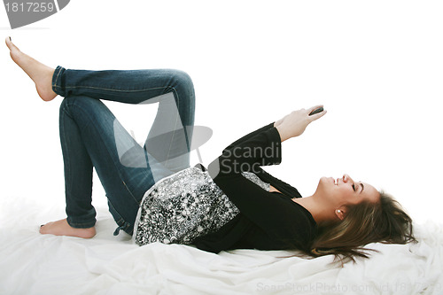 Image of Relaxed young woman sending a text message lying on the bed