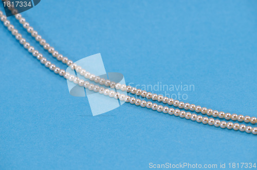 Image of Pearl necklace fragment closeup on blue background 