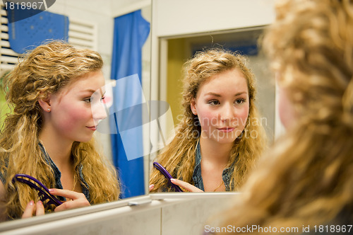 Image of pretty teenager combing her hair